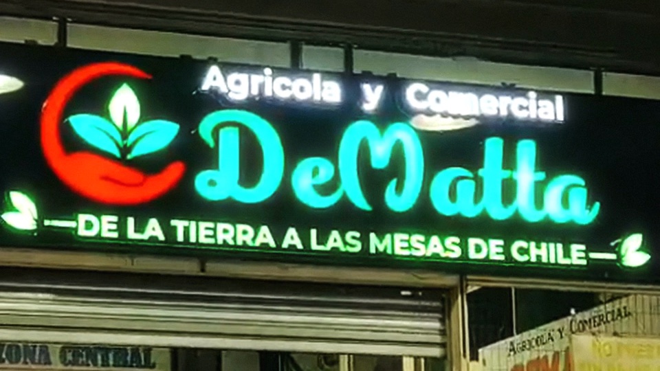 Letrero de Agrícola y Comercial DeMatta encendido de noche