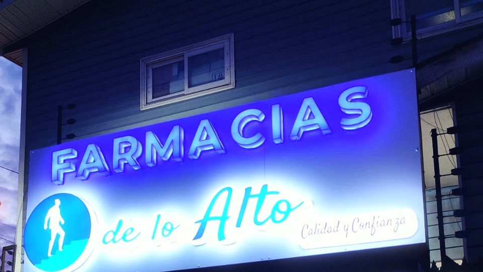 Letrero de Farmacias de lo Alto encendido de noche